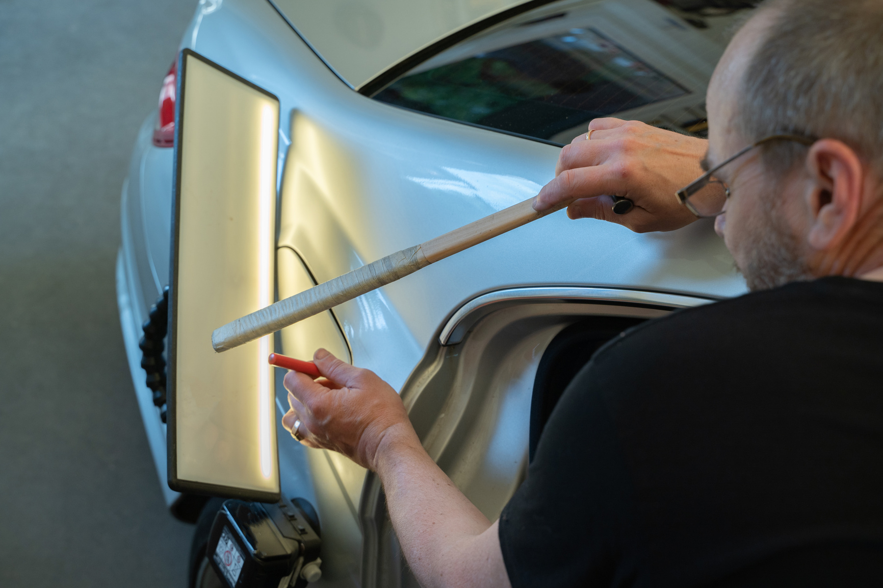 Process of Repairing Dents On Car Body. Technician Is Working Using Professional Tools For Paintless Dent Repair. Car Bodyworks PDR Technology